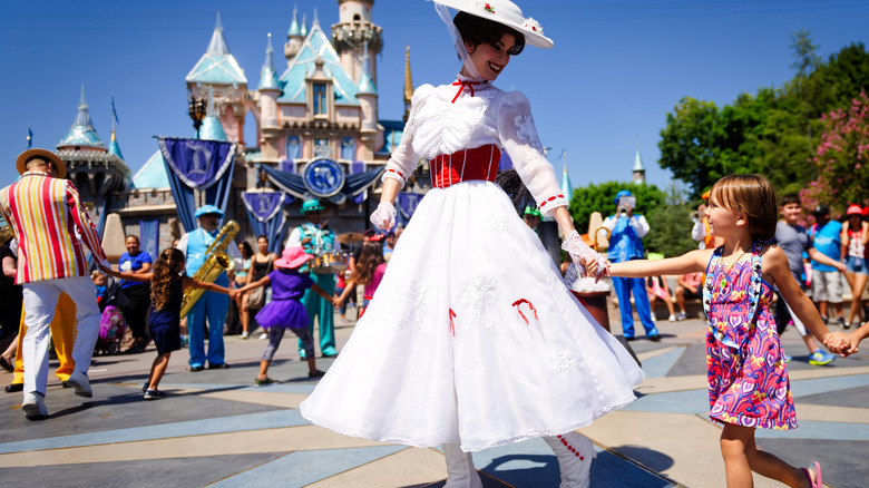 A Mary Poppins actress holding a young girl's hand at Disneyland
