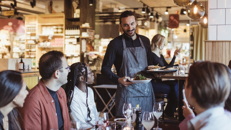 A waiter serves a group of young people