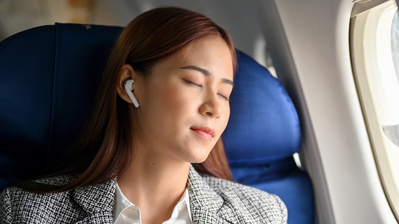 woman sleeping on airplane wearing airpods