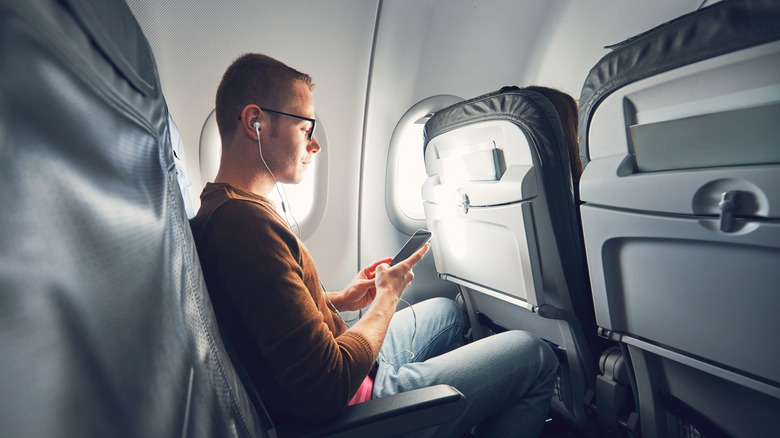 A man using his phone on a plane.