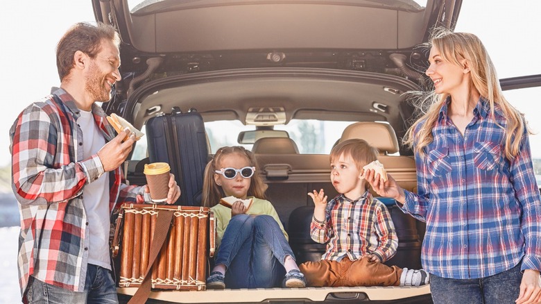 family on road trip eating snacks in back of car