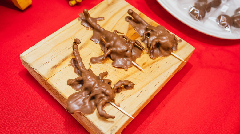 Scorpions covered in chocolate and served on a wooden board.