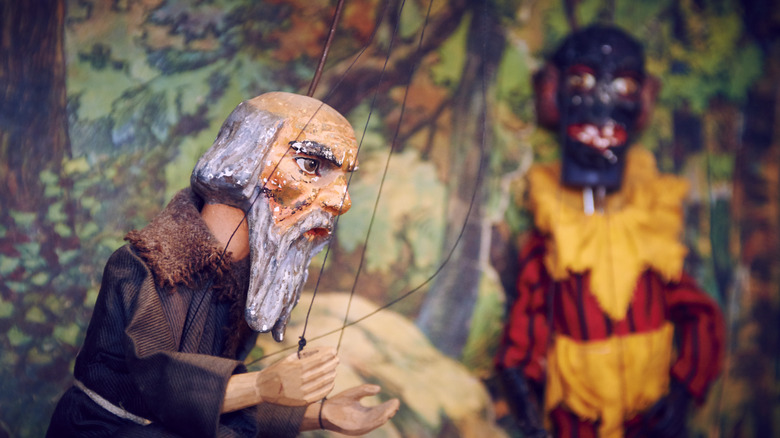 Handmade wooden puppet theater. Monk and devil. Selective focus