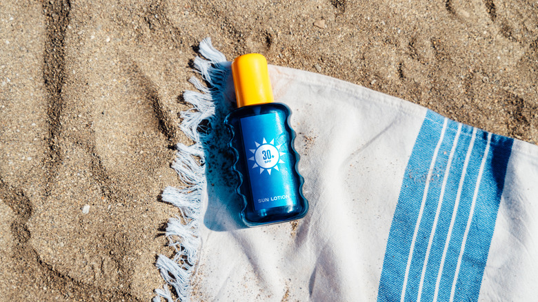 bottle of sunscreen on beach towel