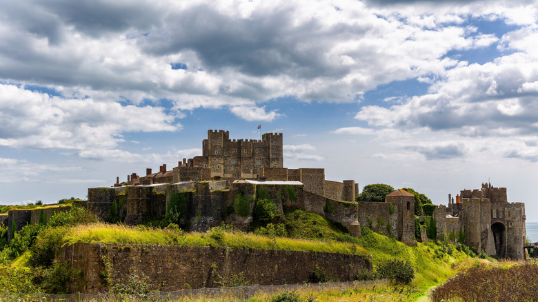 Medieval stone fortress of Dover Castle surrounded by lush green ramparts and walls.