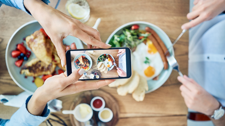 person photographing meal with phone