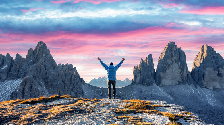 A tourist throws their arms out on the Tre Cime di Lavaredo hike