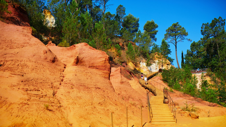 Staircase running through vibrant red hills at the Sentier des Ocres in France.