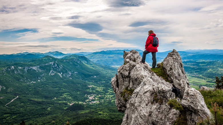 A hiker standing on a cliff in the mountains of Slovenia and gazing at the scenery.