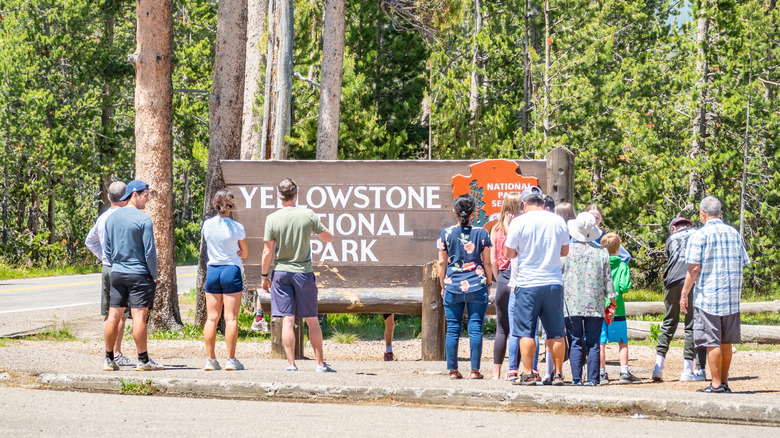 people standing next to the entry to Yellowstone National Park