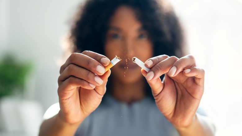 A woman breaks a cigarette in half