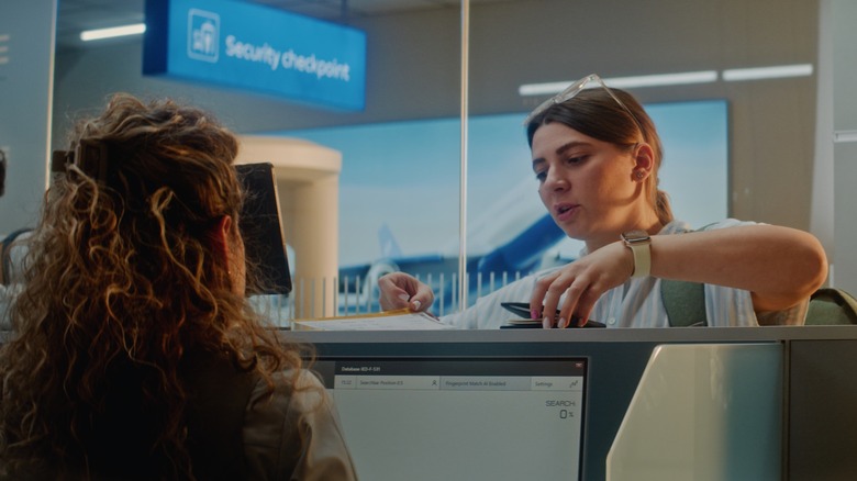 A women standing at passport security check point with passport officer
