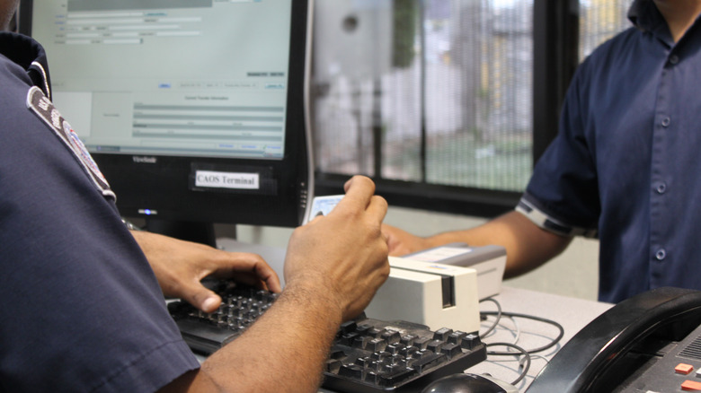 A Customs officer looking at a passengers I.D. card at security