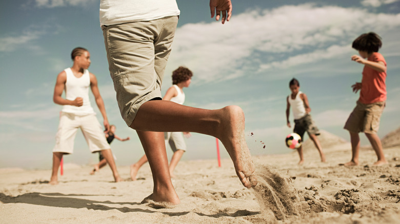 People playing barefoot on the beach