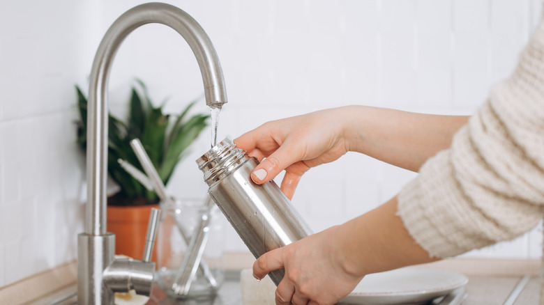 woman filling reusable water bottle