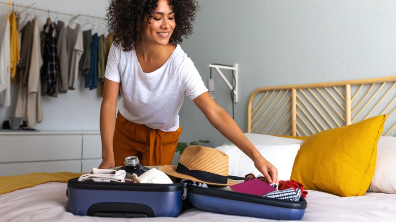 woman packing luggage on bed