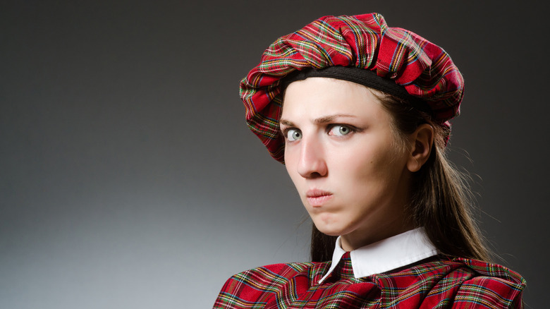 A woman dressed in traditional Scottish attire looks annoyed