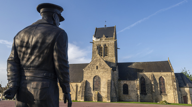 metal statue of a soldier looking at the Church of Sainte-Mère-Église
