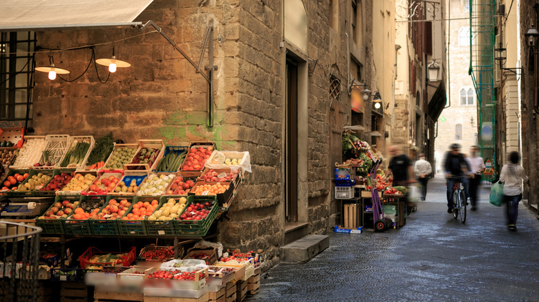 A farmers market on an Italian street corner with food displayed.