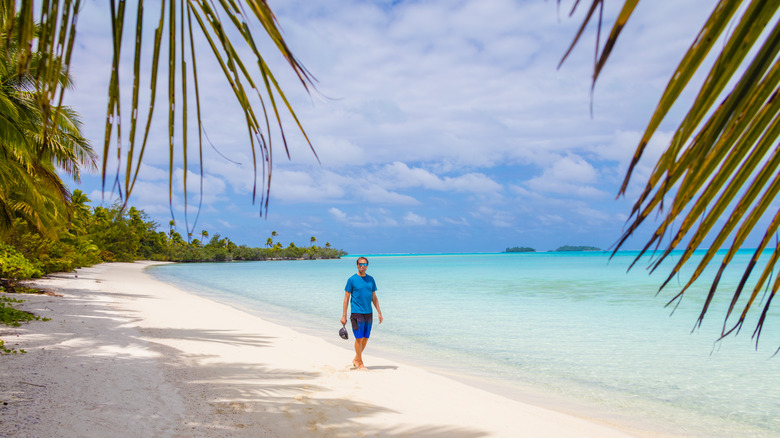 Male walks on the beautiful white sandy beach on the cook islands