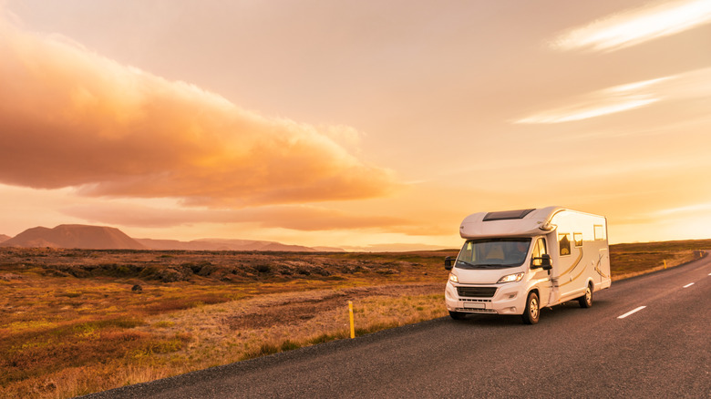 RV on road in desert at sunset