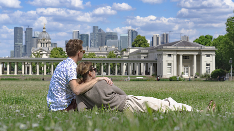 A couple lounges on the grass on a cloudy day in London's Greenwich Park