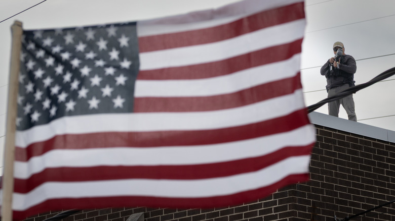 American flag with armed rooftop agent