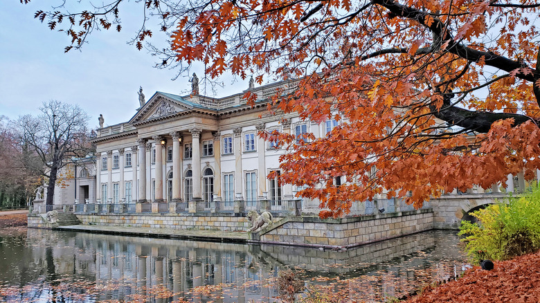 An opulent palace surrounded by water with autumn leaves in foreground