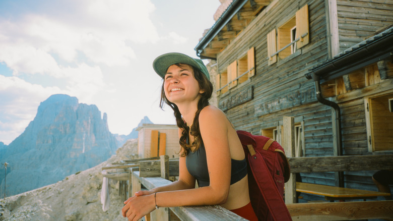 Woman looking out from balcony of mountain lodge