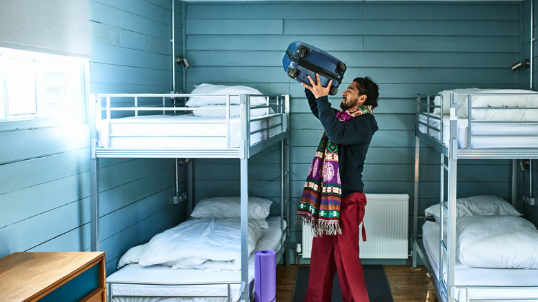 Man putting bag on bed in hostel