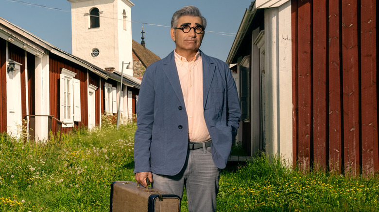 Eugene Levy holding suitcase outside