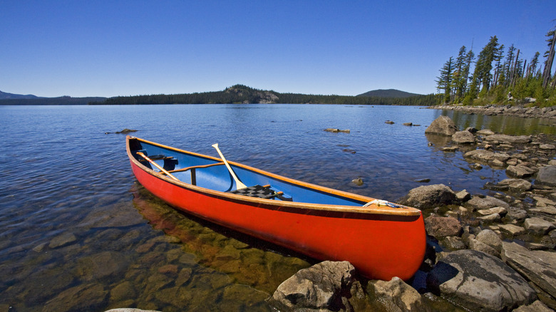 A red canoe sits on the rocky banks of Waldo Lake