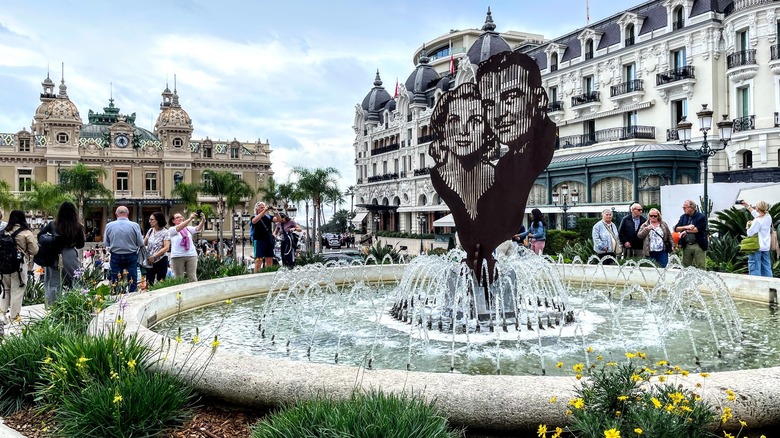 fountain with sculpture, ornate buildings, tourists