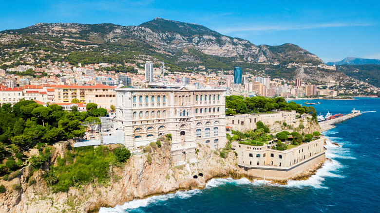 buildings along a cliff, ocean, hill and greenery