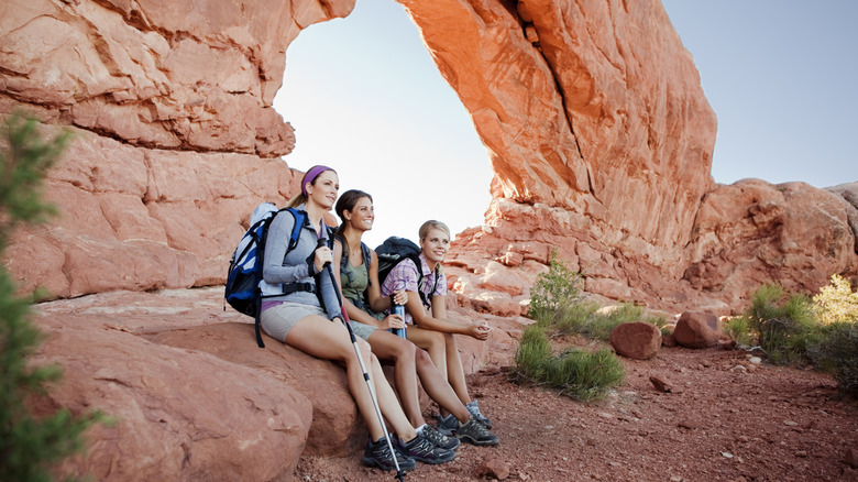 three women sit down while out hiking in Arches National Park, Utah