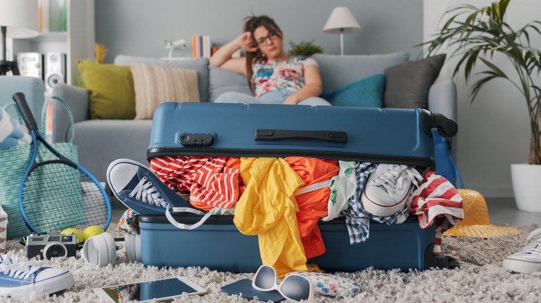 A woman staring at her overpacked suitcase
