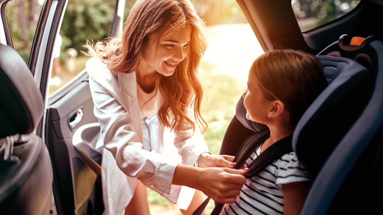 A mom buckling in her daughter 