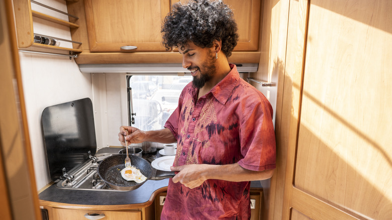 Man cooking eggs in an RV kitchen
