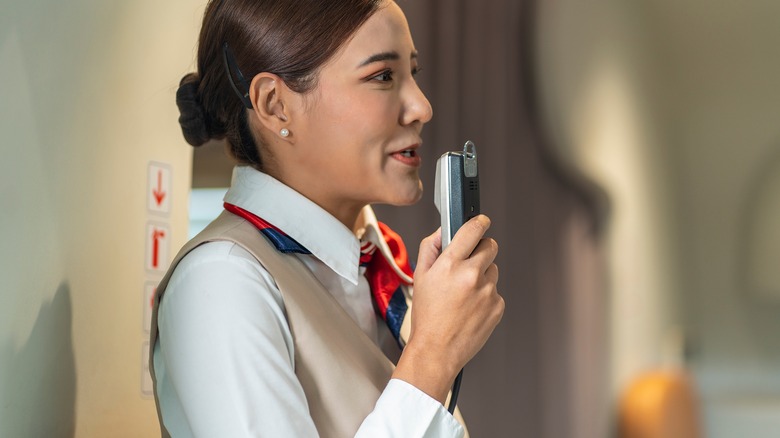 Flight attendant speaking into intercom