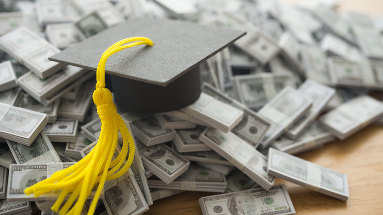 Graduation cap on top of a pile of dollar bills