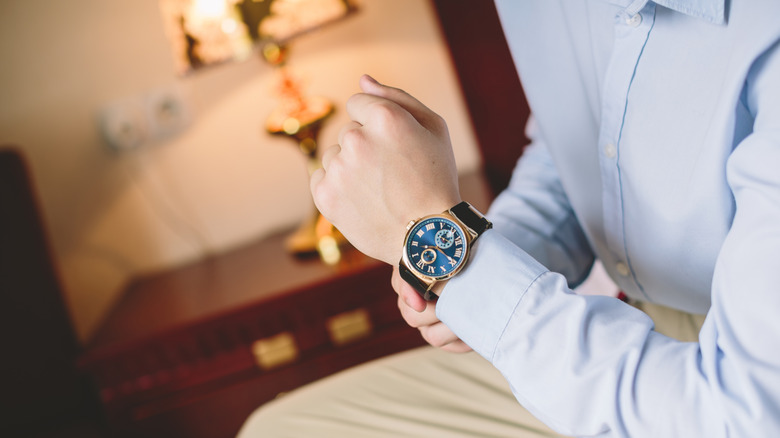 A man wearing an expensive watch in a nice hotel room