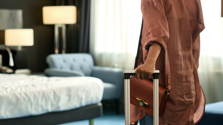 woman in hotel room and holding suitcase
