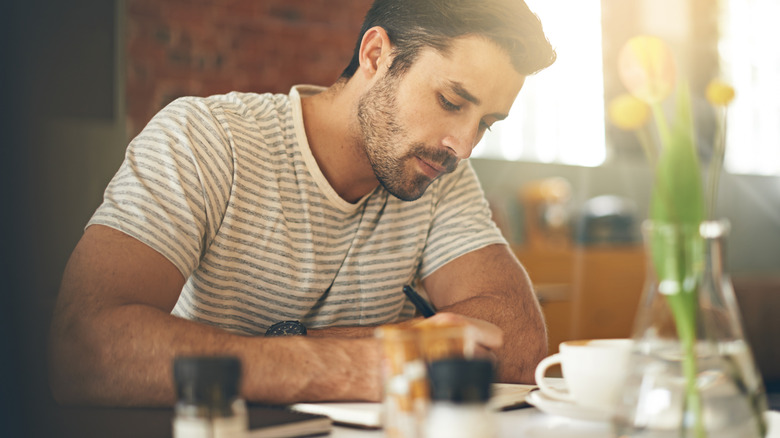 A man writes in his journal in a restaurant