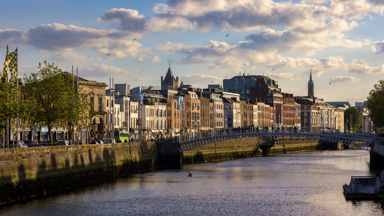View from afar of Pedestrians crossing the Ha'penny Bridge over the River Liffey in Dublin, at sunset.