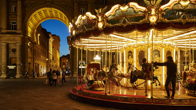 A merry go round lit up at night in a plaza in Florence, Italy