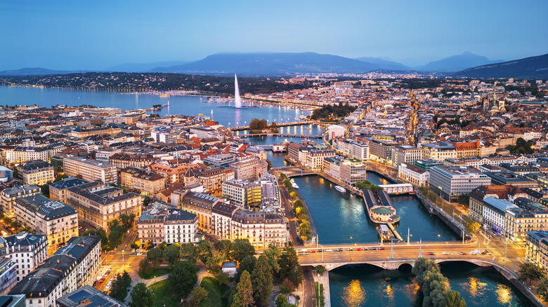 Geneva, Switzerland skyline view towards the Jet d'Eau fountain in Lake Geneva at twilight.