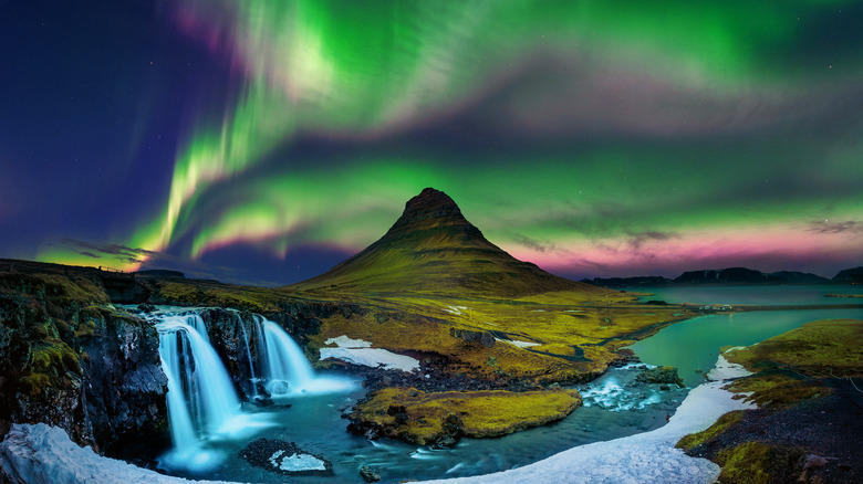 Colorful Northern lights over mountain and waterfalls