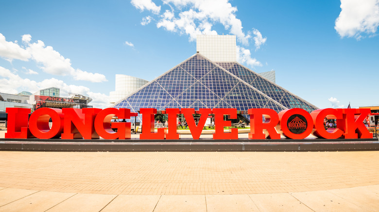 Red block letters reading LONG LIVE ROCK in front of a glass pyramid