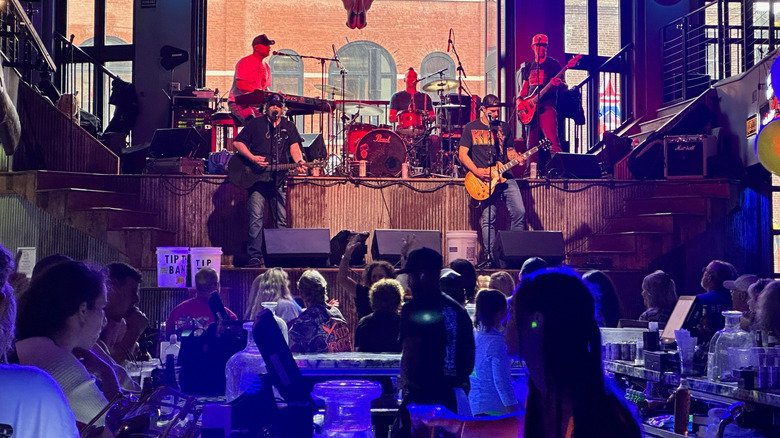 Band performs on stage with audience around tables