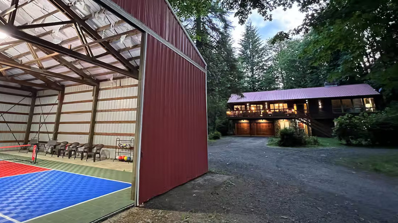 A roofed pickleball court with doors open and a house in the background